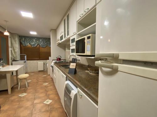 格拉玛多LUXUOSO APT ALMERIS PECCIN no Centro de GRAMADO的厨房配有白色橱柜和台面