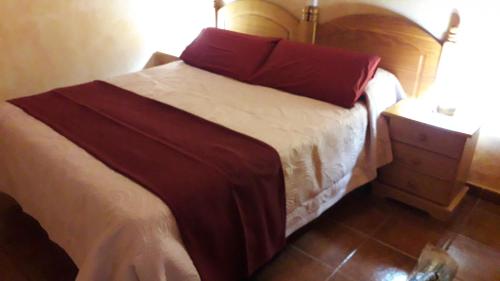 拉斯卡萨斯Casa Rural Abuelo Pancho的一张床上的床上红色枕头