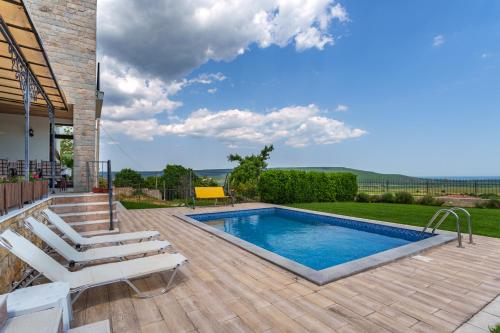 罗格其维Villa Poemia的房屋旁的游泳池设有甲板和椅子