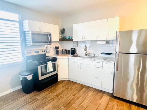 乌马考Home for your stay的厨房配有白色橱柜和不锈钢冰箱
