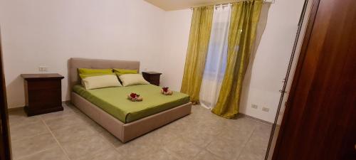 西尼斯科拉Kolbe's house的一间卧室配有一张带绿色床单和黄色窗帘的床