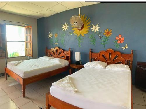 AltagraciaEl Mirador Ecológico, Ometepe的墙上花卉画的房间里,有两张床
