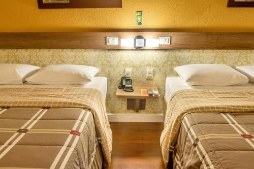 圣利奥波尔杜Hotel 10 São Leopoldo的酒店客房设有两张床和一张桌子上的电话