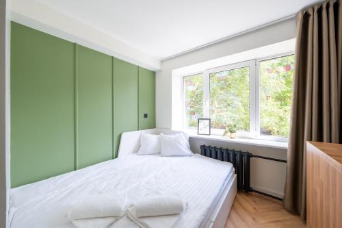 塔林Tallinn Oasis Studios by RevalHome的一间卧室设有一张带绿色墙壁和窗户的床。