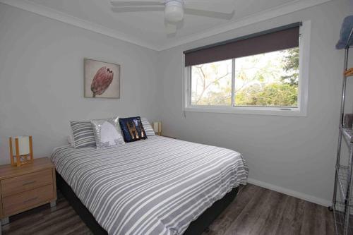 科夫斯港Magnolia Cottage的白色的卧室设有床和窗户