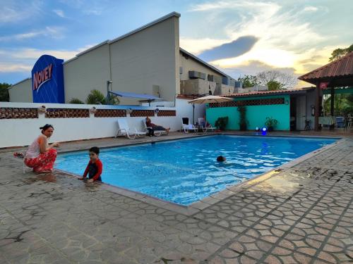 普拉亚科罗纳多Hotel Coronado Inn的女人和孩子在游泳池玩耍