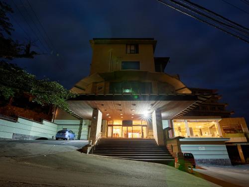 东伊豆町Tabist Izu Atagawa Onsen Hotel Gyokuryu的一座建筑,前方有楼梯,晚上