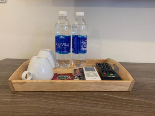 内排NEW SKY AIRPORT HOTEL NỘI BÀI的装有瓶装水和遥控器的木制托盘