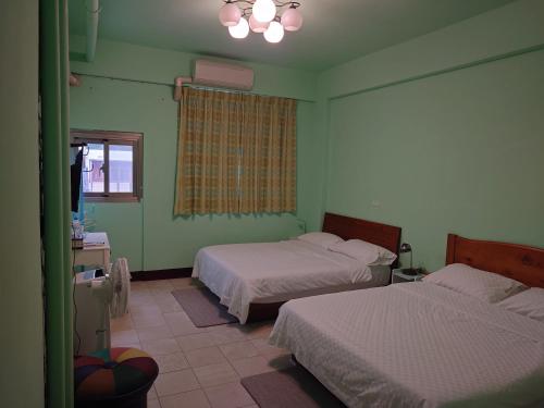 富里里山旅棧民宿 Li Shan Homestay的绿色的客房设有两张床和窗户。