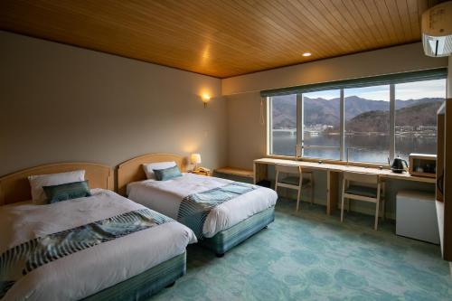 富士河口湖富士湖酒店的一间卧室设有两张床、一张桌子和一个窗口。