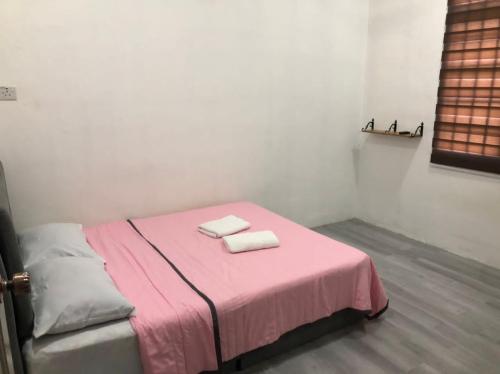 丰盛港Rasa Sayang Homestay Mersing的一间设有粉红色床铺的房间,上面有两条毛巾
