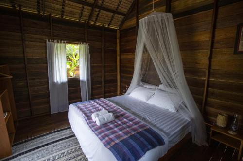 琅勃拉邦Naga Lodge的窗户客房内的一张带天蓬的床