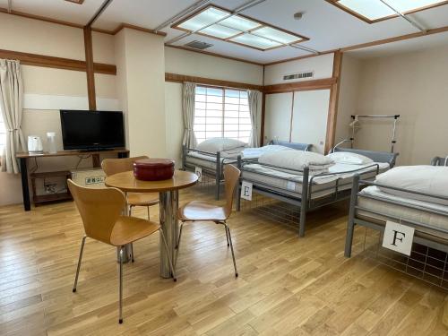 富士河口湖河口湖站旅馆的一间设有四张床和一张桌子及椅子的房间