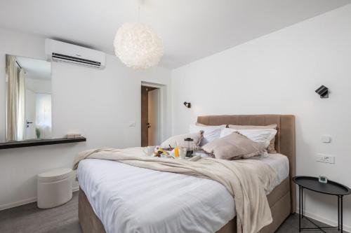 罗波里卡Cosy holiday home Infinity with pool and BBQ的一间卧室配有一张带白色床单和镜子的床
