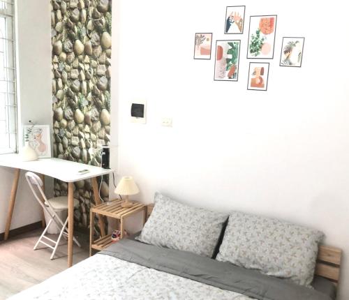 河内Mika Homestay Simple & Cozy的一间卧室配有一张床和一张书桌,墙上挂着图片