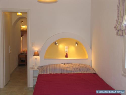 帕罗斯岛Afroditi studios的一间卧室配有一张红色的床和黄色床头板