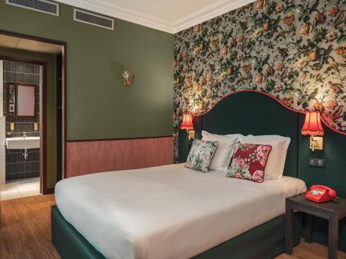 巴黎布列塔尼酒店的一间卧室配有一张带花卉壁纸的大床