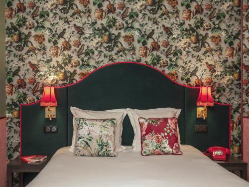 巴黎布列塔尼酒店的卧室配有一张带两个枕头的床和花卉壁纸