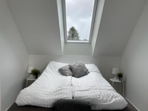 NordbyOasen Samsø的白色客房的一张床位,设有窗户