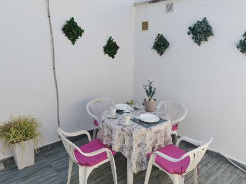 赫雷斯-德拉弗龙特拉Casasjerezanas Loft Las Flores的天井上配有带粉色和白色椅子的桌子
