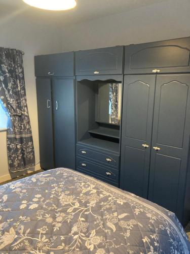 利特里姆Clinton’s cottage的一间卧室配有一张床和一个蓝色的橱柜