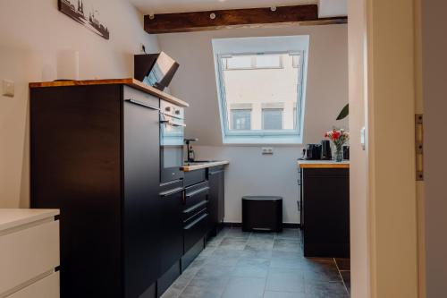 不莱梅Luxuriöse und stilvolle Ferienwohnung in bester Lage Bremens的厨房配有黑色橱柜和窗户。