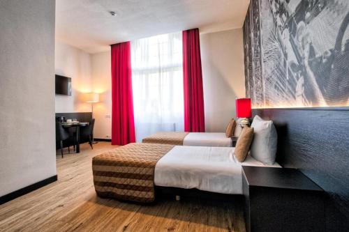 蒂尔堡Onderwijshotel De Rooi Pannen Tilburg的酒店客房,配有两张带红色窗帘的床