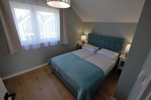 弗瓦迪斯瓦沃沃Domki Luan Village的一间卧室设有蓝色的床和窗户。