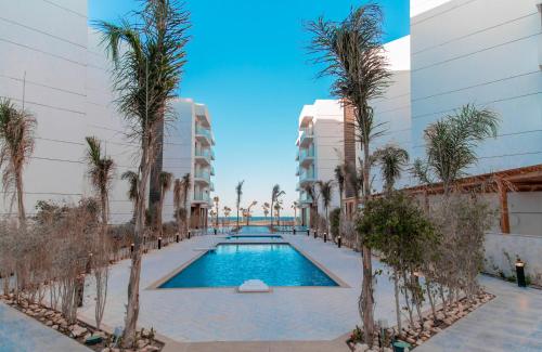 塞得港Porto Said Tourist Resort Luxury Hotel Apartment的一座楼前棕榈树游泳池