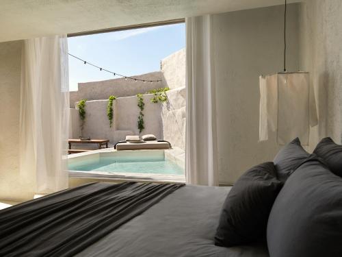 凯勒里瓦迪Nomad Mykonos - Small Luxury Hotels of the World的一间卧室设有一张床和一个游泳池