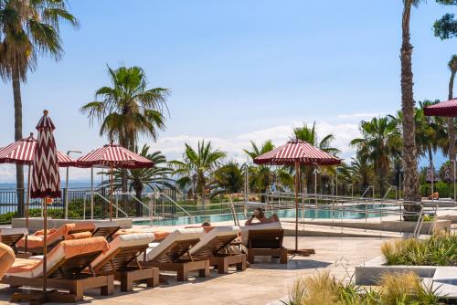 马贝拉El Fuerte Marbella的一个带游泳池的度假胜地,人们坐在椅子和遮阳伞上