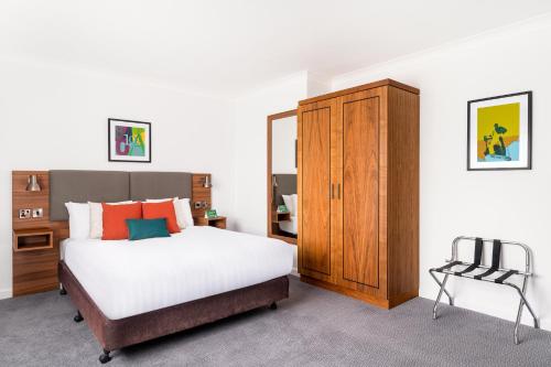 布罗姆斯格罗夫假日伯明翰布罗姆斯格罗夫酒店的一间卧室配有一张床、一个橱柜和一把椅子