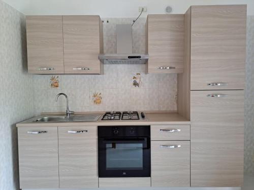 PianilloIl Rio Penise的厨房配有木制橱柜、炉灶和水槽。