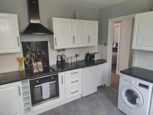 贝克斯希尔Bexhill Stunning 2 bedroom Sea Front Bungalow的厨房配有白色橱柜和洗衣机。