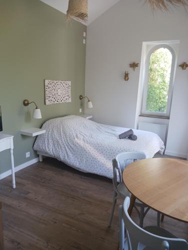 南特La laiterie de la Plume的卧室配有一张床和一张桌子及椅子