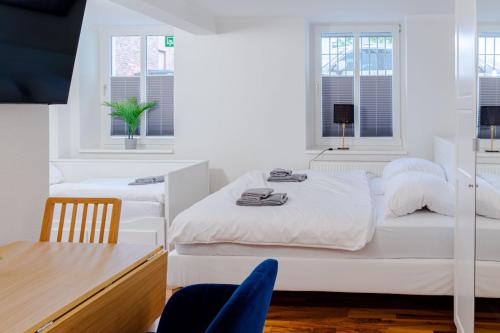 罗斯托克Apartments am Hauptbahnhof的白色卧室配有两张床和一张桌子
