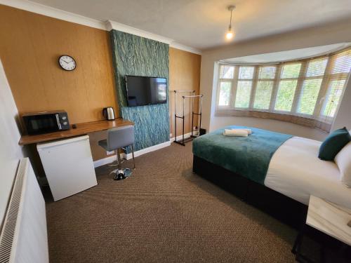 伯明翰Solihull Shared House的酒店客房设有一张床、一张书桌和一台电视机。