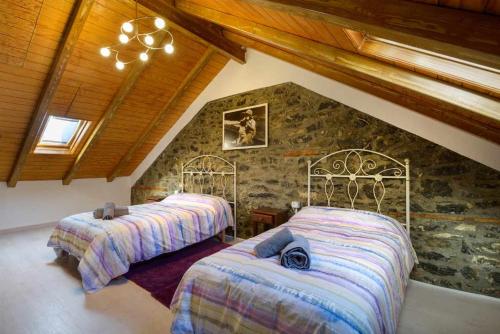 潘蒂科萨Casitas centro panticosa的一间卧室设有两张床和石墙