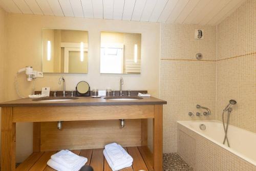 圣克莱门特德巴穿靴子的猫酒店的浴室配有两个盥洗盆和浴缸。