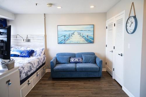 默特尔比奇HGTV Inspired Oceanfront Studio - Myrtle Beach Resort的一间卧室配有一张床和一张蓝色的沙发