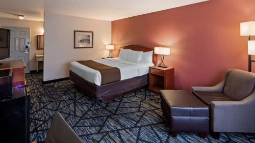 奥本SureStay Plus Hotel by Best Western Auburn的配有一张床和一把椅子的酒店客房
