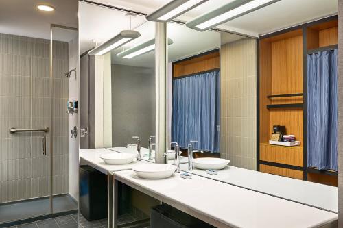 奥罗拉Aloft Denver Airport at Gateway Park的一间带三个水槽和镜子的浴室