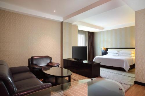 棉兰棉兰福朋喜来登酒店的酒店客房,配有床、沙发和椅子