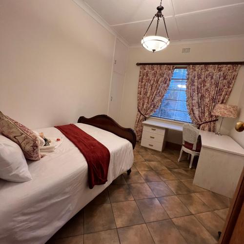约翰内斯堡Peaceful@Swansea In Rosebank-Parkwood的一间卧室配有一张床、一张书桌和一个窗户。