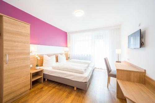 慕尼黑S16酒店的一间卧室配有一张床、一张书桌和一台电视。