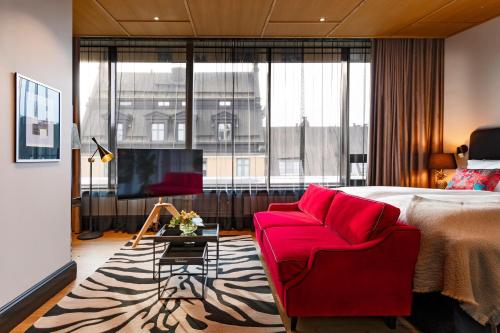赫尔辛基Hotel U14, Autograph Collection的酒店客房配有红色的沙发和床。