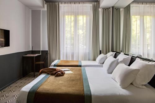 巴黎加斯顿酒店的带窗户的酒店客房内的两张床