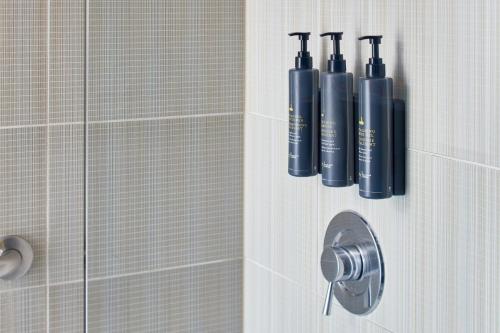 阿什本杜勒斯机场北雅乐轩酒店的一间带淋浴的浴室,墙上装有两瓶