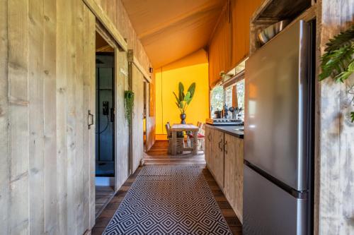 泽沃德Sunny Trio的厨房设有黄色的墙壁和不锈钢冰箱。