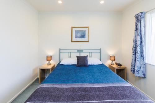 北帕默斯顿柯莱特会议中心汽车旅馆 的一间卧室配有蓝色的床和2个床头柜